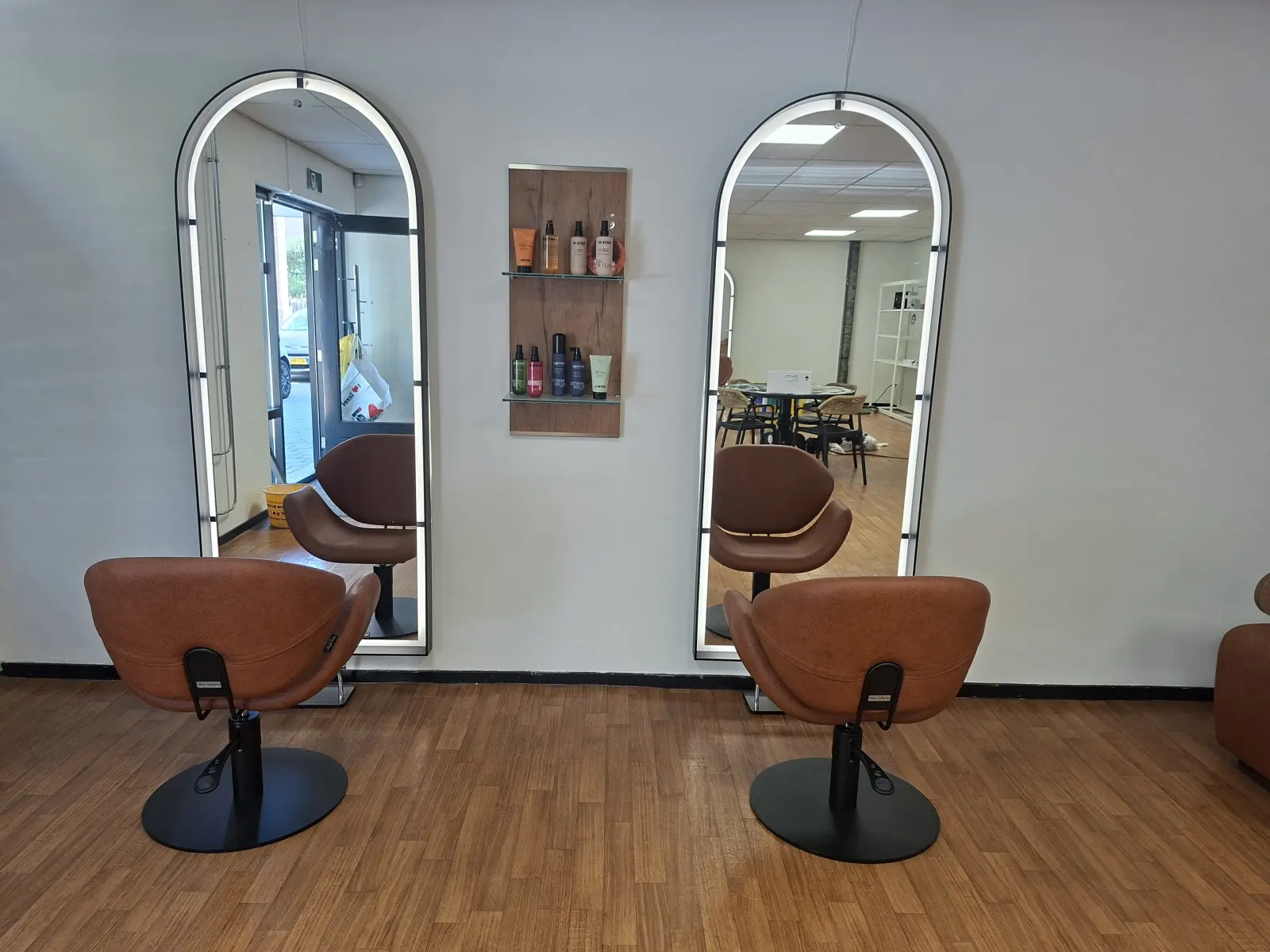 Twee kappersstoelen voor verlichte spiegels in de salon